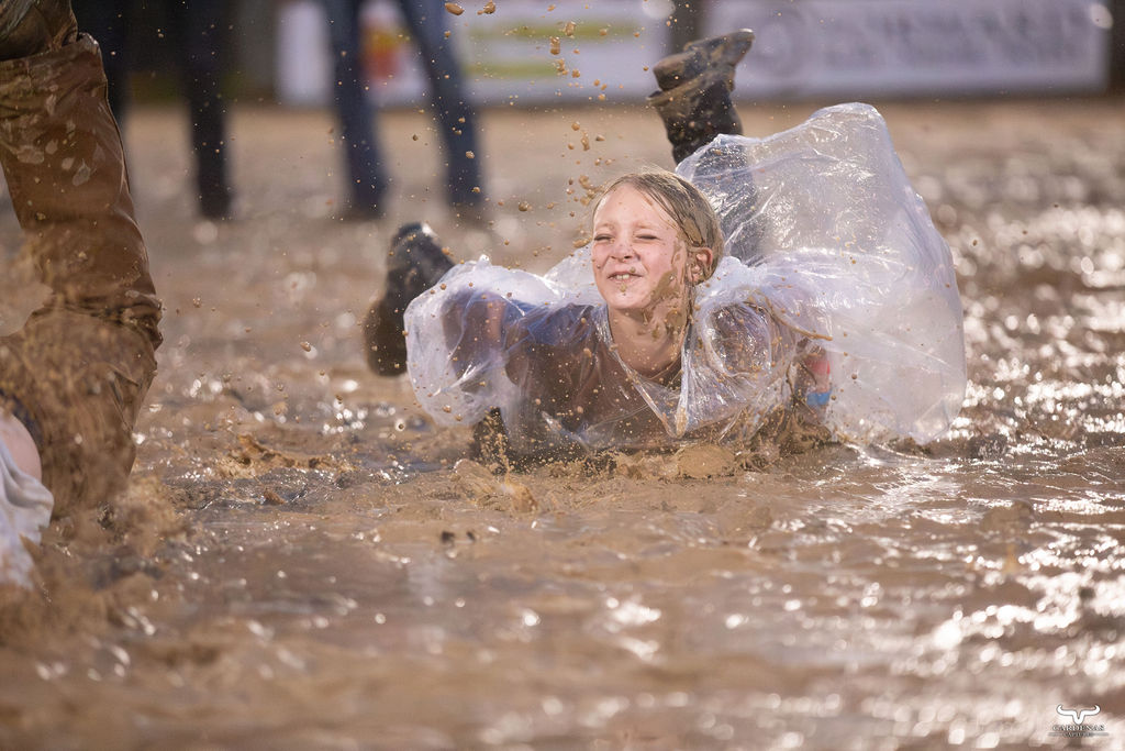 Kid laughing while sliding through the mud at the rodeo